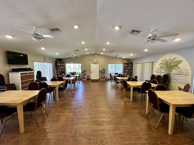 dining area with a ceiling fan, visible vents, wood finished floors, and vaulted ceiling