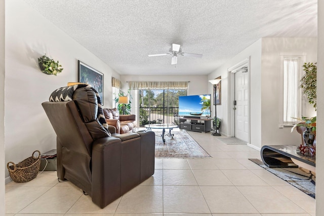 living room featuring light tile patterned floors, baseboards, a ceiling fan, and a textured ceiling