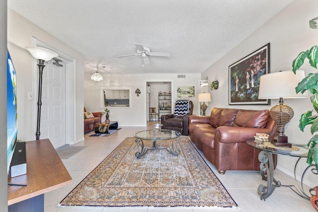 tiled living area featuring baseboards, a ceiling fan, a textured ceiling, and visible vents