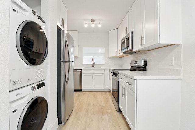3107 SW 20th Ter Unit C-1, Delray Beach, FL 33445 - clothes washing area featuring stacked washing maching and dryer, laundry area, light wood finished floors, and a sink