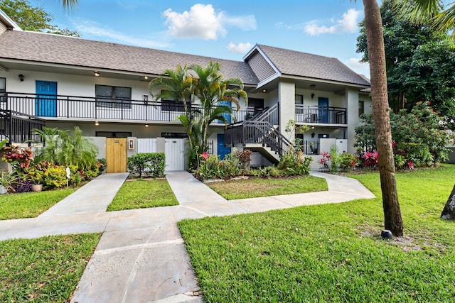 3107 SW 20th Ter Unit C-1, Delray Beach, FL 33445 - view of front facade featuring a front yard, stairs, a shingled roof, and stucco siding