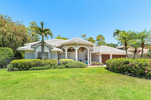 582 Cypress Green Cir, Wellington, FL 33414 - mediterranean / spanish-style home with an attached garage, a front lawn, stucco siding, and fence