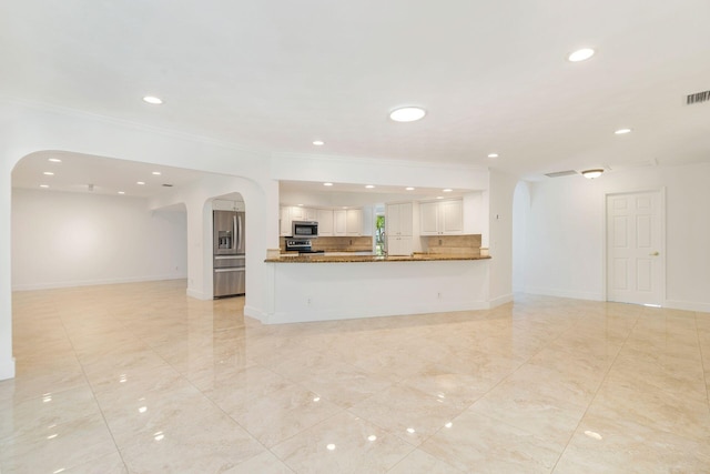unfurnished living room featuring ornamental molding, arched walkways, recessed lighting, baseboards, and light tile patterned floors