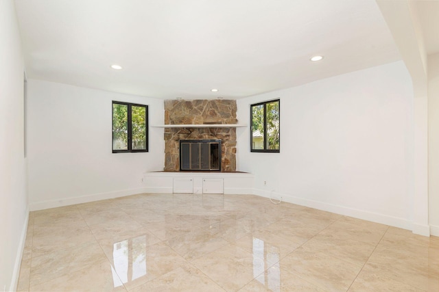unfurnished living room with plenty of natural light, a stone fireplace, recessed lighting, baseboards, and marble finish floors
