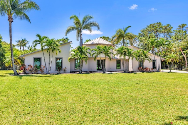 mediterranean / spanish home with stucco siding, a front yard, and a standing seam roof