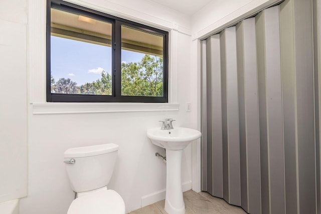 bathroom with toilet, tile patterned flooring, and a sink