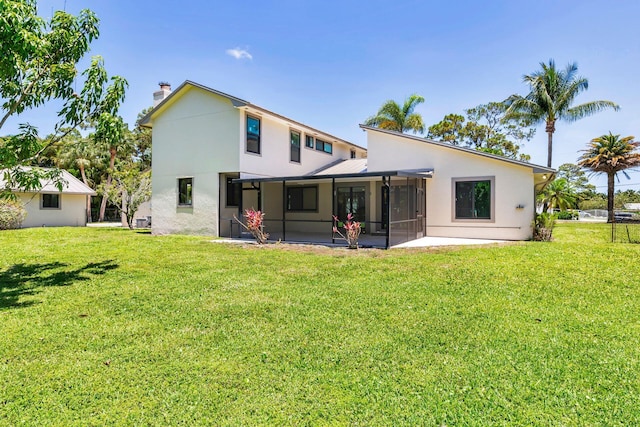 rear view of house with a sunroom, a lawn, and stucco siding