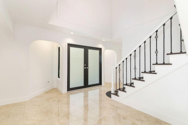 entryway with arched walkways, stairway, french doors, baseboards, and recessed lighting