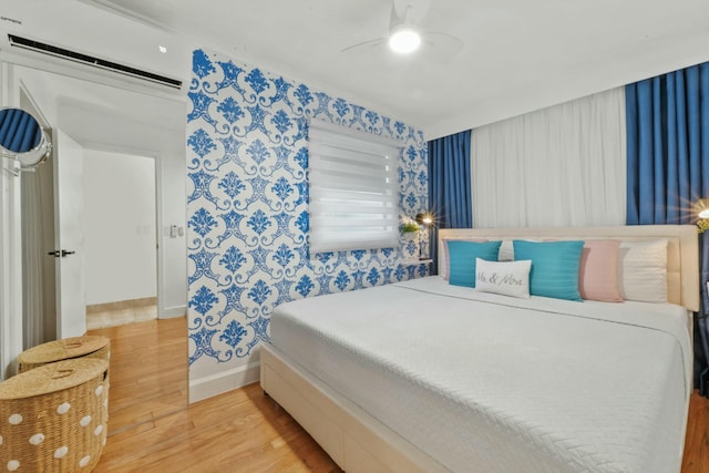 951 Selkirk St, West Palm Beach, FL 33405 - bedroom featuring a wall mounted air conditioner, a ceiling fan, baseboards, wallpapered walls, and wood finished floors