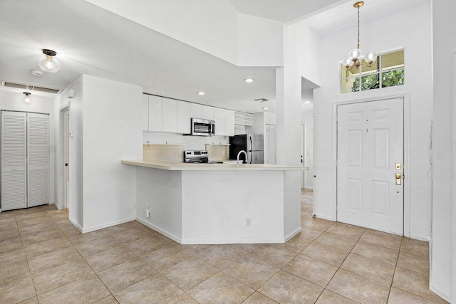 3803 S Lancewood Pl, Delray Beach, FL 33445 - kitchen featuring appliances with stainless steel finishes, light countertops, a peninsula, an inviting chandelier, and white cabinetry