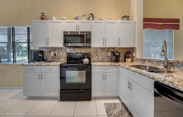 kitchen featuring a sink, light tile patterned floors, backsplash, and black appliances