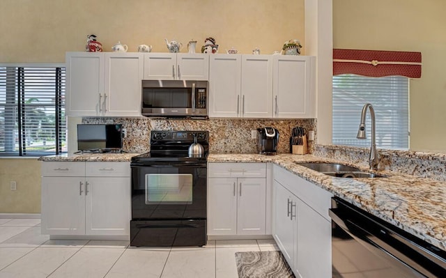 kitchen featuring decorative backsplash, light stone countertops, white cabinets, a sink, and black appliances