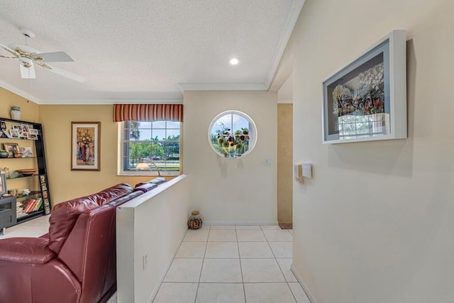 corridor featuring baseboards, ornamental molding, a textured ceiling, and light tile patterned floors