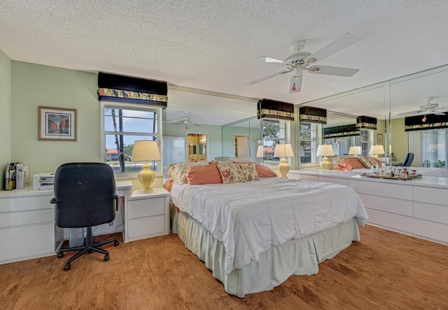 bedroom with a textured ceiling, multiple windows, and light wood-style floors