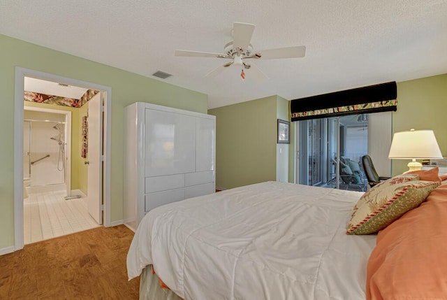 bedroom featuring a ceiling fan, visible vents, wood finished floors, baseboards, and ensuite bathroom