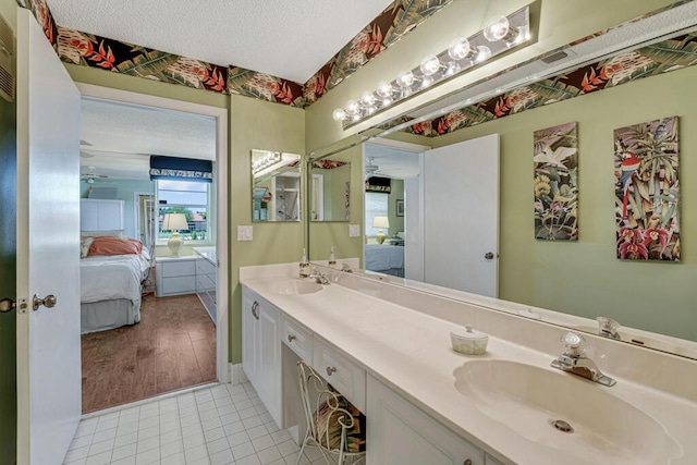 bathroom with double vanity, a textured ceiling, a sink, and ensuite bath