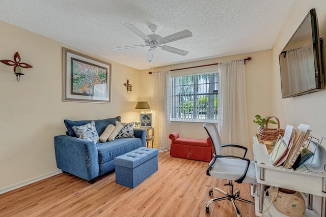 sitting room featuring a textured ceiling, baseboards, a ceiling fan, and light wood-style flooring