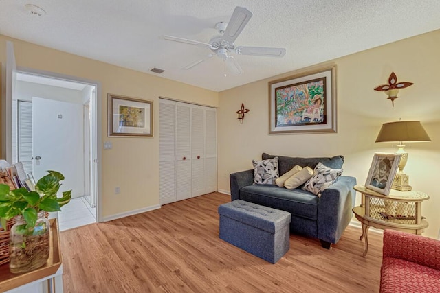 sitting room with visible vents, a ceiling fan, light wood-style flooring, and baseboards