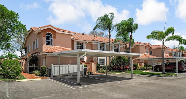 view of front facade with covered and uncovered parking, stucco siding, and a tiled roof