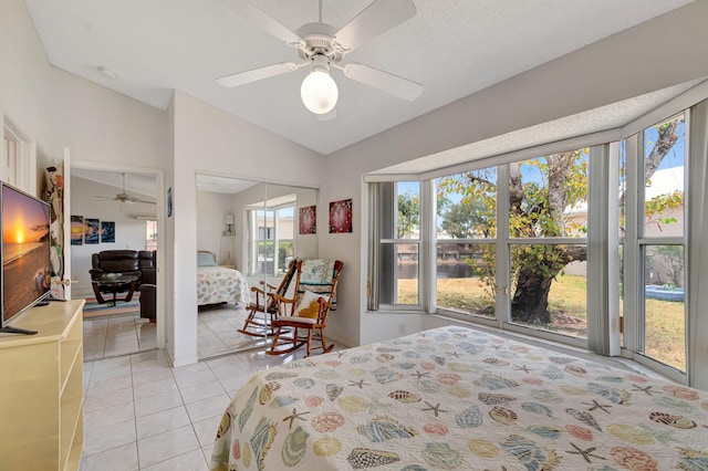 bedroom with light tile patterned floors, a closet, a water view, ceiling fan, and lofted ceiling