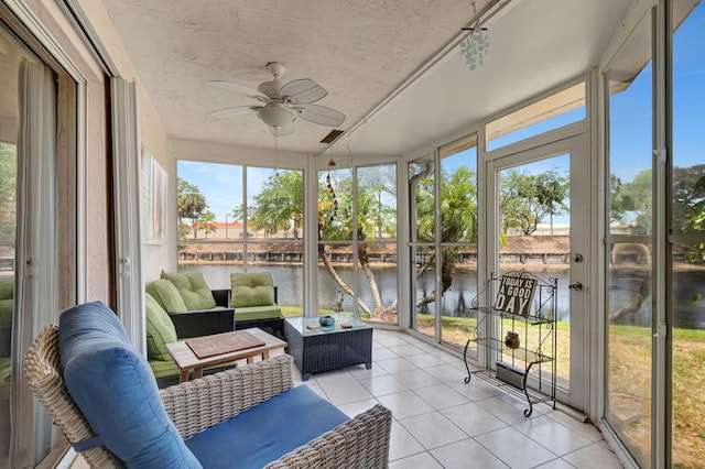 sunroom / solarium featuring ceiling fan, a water view, and an outdoor living space