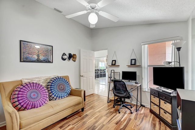 office space featuring a ceiling fan, visible vents, and wood finished floors