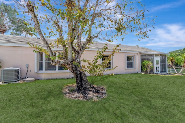 back of property with stucco siding, cooling unit, a lawn, and a sunroom