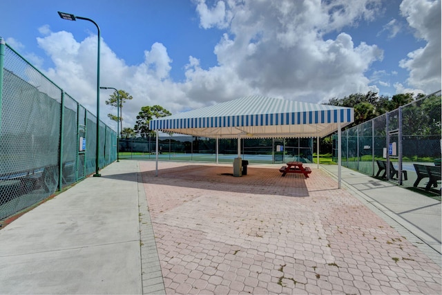 surrounding community with a tennis court and fence