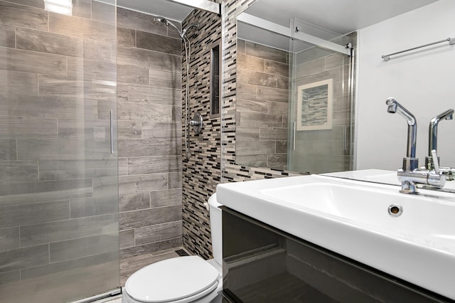 full bathroom with toilet, vanity, and a shower stall
