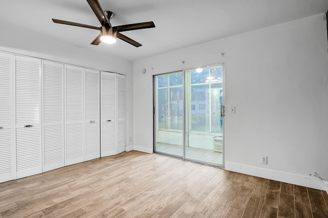 unfurnished bedroom featuring wood finished floors, a closet, access to exterior, and baseboards