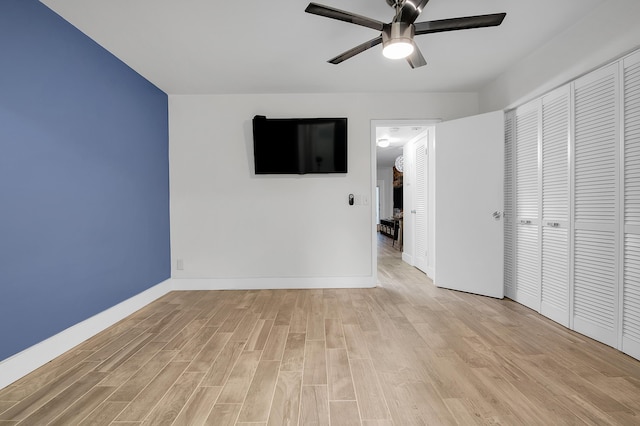 unfurnished bedroom featuring a closet, a ceiling fan, baseboards, and light wood-type flooring