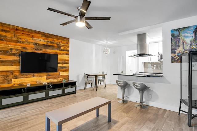 living area with baseboards, wood finished floors, and a ceiling fan