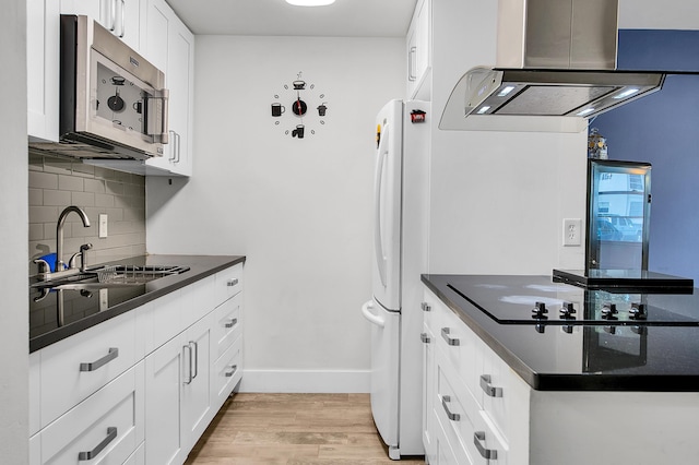 kitchen with freestanding refrigerator, stainless steel microwave, dark countertops, a sink, and island exhaust hood