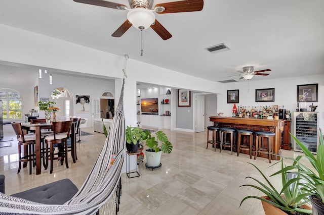 dining space with ceiling fan, visible vents, arched walkways, a dry bar, and marble finish floor