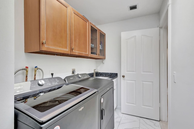 laundry area with visible vents, washing machine and dryer, cabinet space, a sink, and marble finish floor