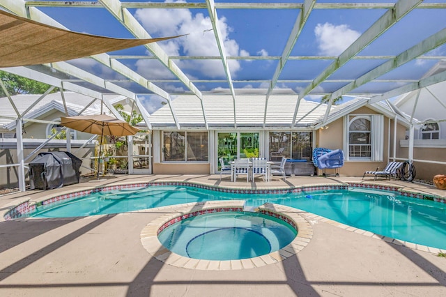 view of swimming pool featuring glass enclosure, a patio area, a pool with connected hot tub, and area for grilling