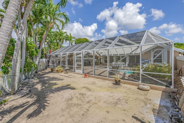 rear view of house featuring glass enclosure, an outdoor pool, and a patio area