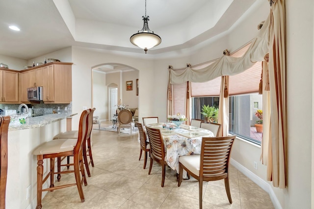 16211 Rosecroft Ter, Delray Beach, FL 33446 - dining area featuring arched walkways, baseboards, a tray ceiling, and light tile patterned flooring
