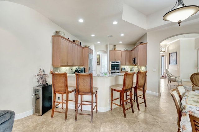 16211 Rosecroft Ter, Delray Beach, FL 33446 - kitchen featuring arched walkways, a peninsula, stainless steel appliances, and tasteful backsplash