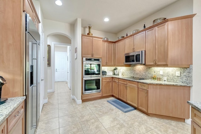 16211 Rosecroft Ter, Delray Beach, FL 33446 - kitchen with appliances with stainless steel finishes, tasteful backsplash, arched walkways, light stone counters, and light tile patterned flooring