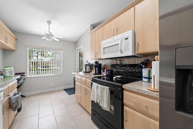 kitchen featuring stainless steel refrigerator, light brown cabinets, white microwave, light countertops, and black electric range