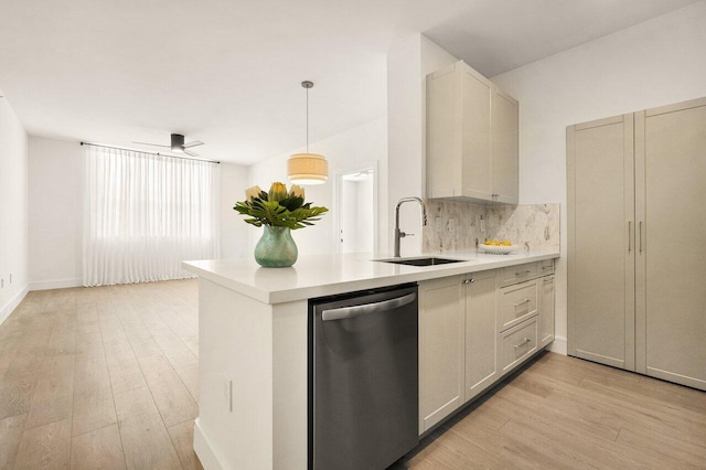 kitchen featuring a sink, light countertops, stainless steel dishwasher, and light wood-style floors