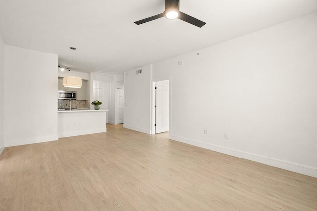 720 S Sapodilla Ave Unit 105, West Palm Beach, FL 33401 - unfurnished living room featuring light wood-style flooring, ceiling fan, and baseboards