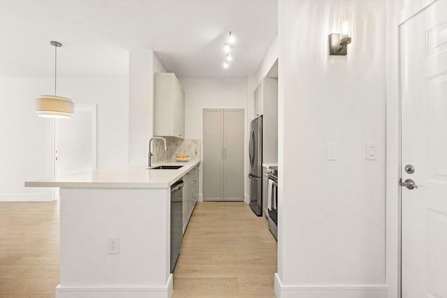 720 S Sapodilla Ave Unit 105, West Palm Beach, FL 33401 - kitchen featuring stainless steel appliances, a sink, light wood-style flooring, light countertops, and a peninsula