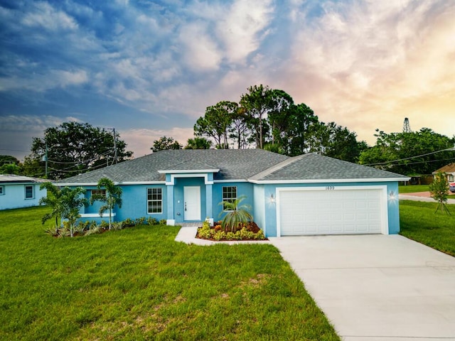 ranch-style house featuring driveway, a front yard, a shingled roof, and an attached garage