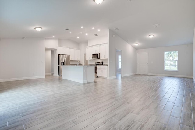 unfurnished living room featuring baseboards, light wood-style flooring, and a sink