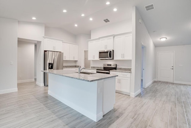 kitchen with a sink, stainless steel appliances, visible vents, light wood-style flooring, and an island with sink