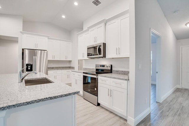 kitchen featuring visible vents, stainless steel appliances, light wood finished floors, and a sink