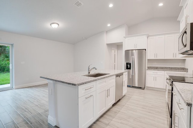 kitchen featuring light stone countertops, an island with sink, stainless steel appliances, a sink, and visible vents