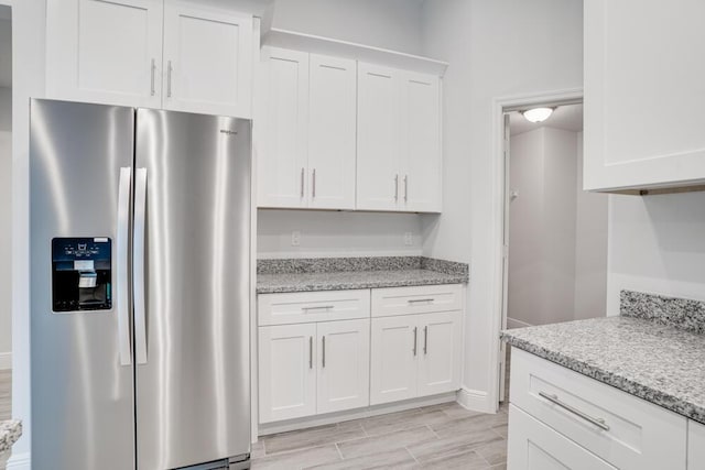 kitchen featuring light wood-style floors, white cabinets, light stone counters, and stainless steel fridge with ice dispenser